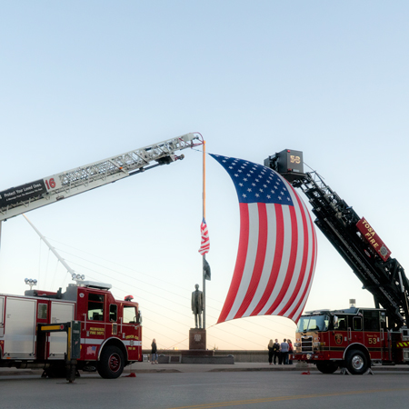 Fire truck ladder towers holding American flag
